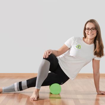 Lisa rollt ihren Oberschenkel auf einer Faszienrolle aus